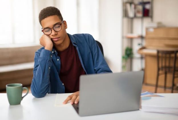 Photo of unfocused sleepy male worker in front of his laptop
