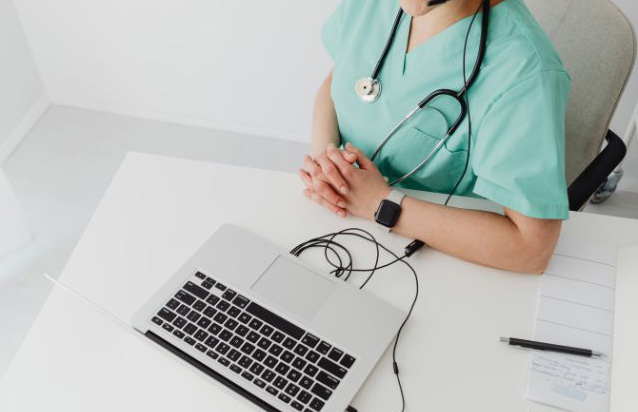 A healthcare provider uses a laptop to conduct a telehealth consultation with a patient