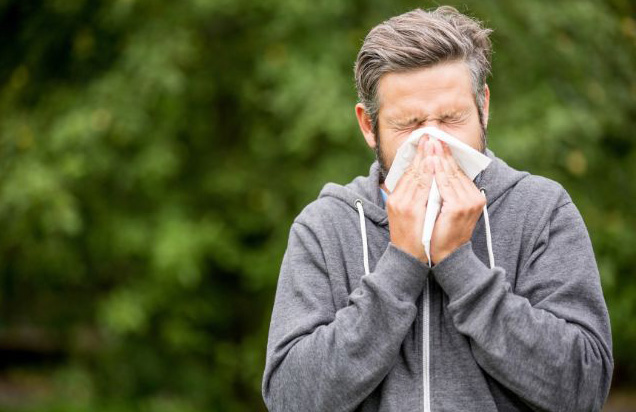 Person showing sneezing, showing symptoms of seasonal allergies
