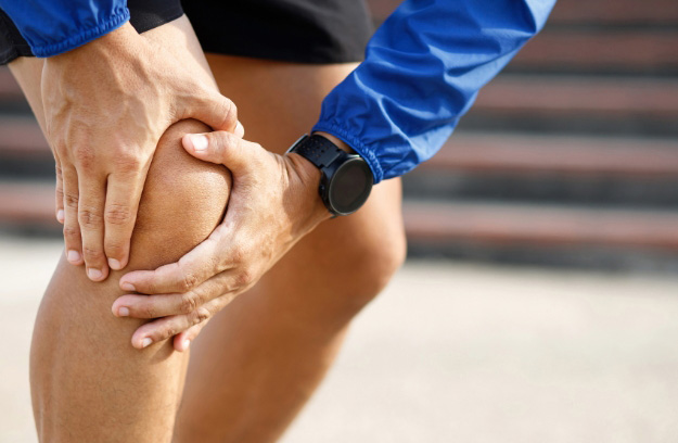 Photo of person holding his knee for the blog post on advanced tendon healing protocols